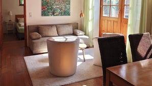 A cozy living room with a wooden ceiling, a sofa, a coffee table, and a dining area with a table and chairs. - Apartment in Geiersthal (Weilmünster)