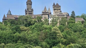 A castle with multiple towers and a prominent central tower, surrounded by dense greenery. - Apartment in Geiersthal (Weilmünster)