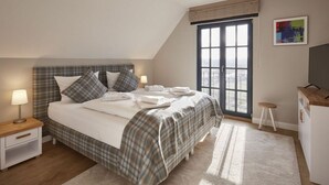 A bedroom with a bed, bedside tables, a desk, and a window with a view. - Luxury Roof Villa With Sauna and Fireplace (Dranske)