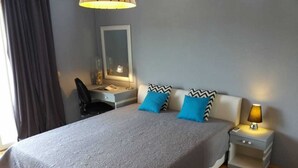 Une chambre à coucher avec un grand lit, deux oreillers, un bureau, une chaise, un miroir et une lampe de chevet.
