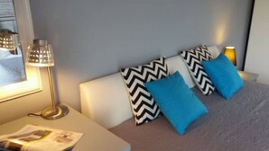 Une chambre d’hôtel bien rangée, avec un lit, des oreillers, une table de chevet avec une lampe et un magazine.