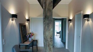 A hallway with exposed wooden beams, a dining area with chairs and a table, and wall-mounted lighting. - Appealing Apartment in Westerstede (Westerstede)