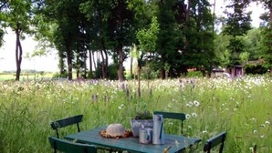 A picnic table with a basket and a metal container in a field of wildflowers. - Appealing Apartment in Westerstede (Westerstede)