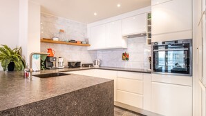 Uma cozinha moderna com bancada de granito, armários brancos e forno embutido.