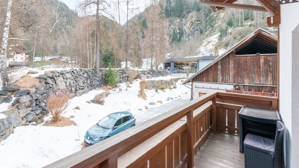 A wooden deck with a view of a snowy landscape and a car parked in the driveway. - Nice Apartment in Langenfeld With Sauna (Laengenfeld)