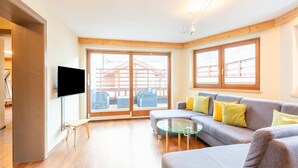 A modern living room with a grey sofa, a glass coffee table, and a flat-screen TV mounted on the wall. - Nice Apartment in Langenfeld With Sauna (Laengenfeld)