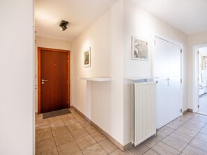 A hallway with a wooden door, a white radiator, and a framed map on the wall. - Apartment in St-idesbald With Sea View (Koksijde)