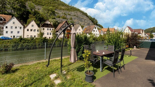 A patio with a table and chairs, surrounded by a metal fence, with houses in the background. - Sauna Retreat in Sulz (Sulz am Neckar)