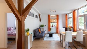A modern living room with a sofa, a dining table, and a kitchen area. - Sauna Retreat in Sulz (Sulz am Neckar)