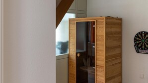 A room with a wooden cabinet, a dartboard, and a window. - Sauna Retreat in Sulz (Sulz am Neckar)