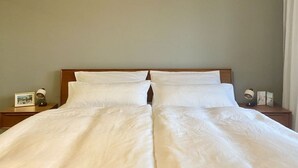 A double bed with white linens, a wooden headboard, and two bedside tables with lamps and picture frames. - Trappen Comfortable Holiday Residence (Birresborn)