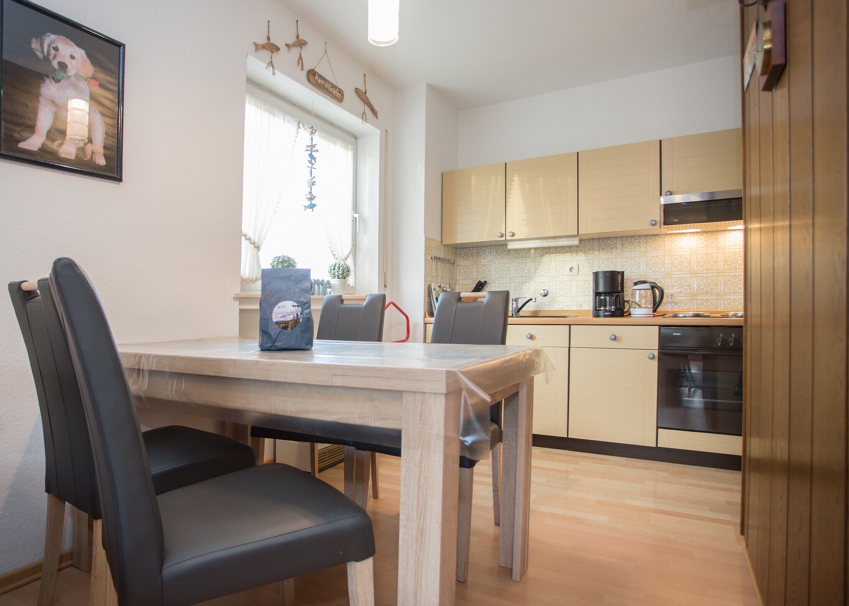 Una cocina moderna con armarios de madera, una mesa de comedor con sillas y un refrigerador.