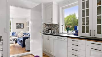 A modern kitchen with white cabinets, a black countertop, and a window with a view of greenery outside.