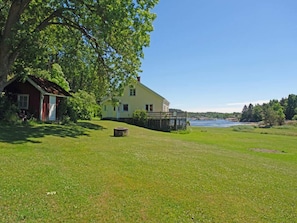 A house with a large lawn and a body of water in the background. - 5 Star Holiday Home in Stromstad (Stromstad)