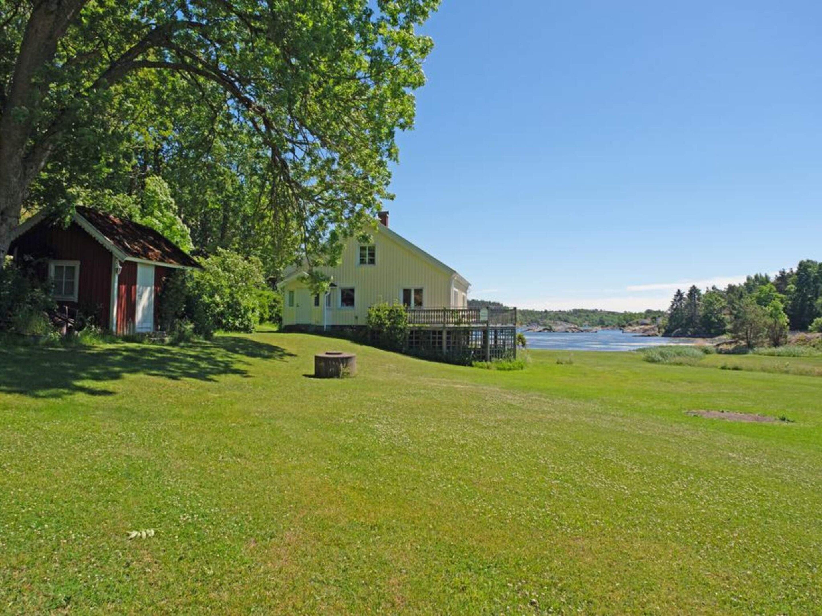 A house with a large lawn and a body of water in the background.