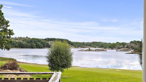 A view of a lake with a grassy area and a wooden fence in the foreground. - 5 Star Holiday Home in Stromstad (Stromstad)