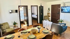 A dining area with a wooden table set for four, surrounded by chairs. There is a television mounted on the wall to the right. - Villa in Malaga, Private Pool and sea View (Cartama)