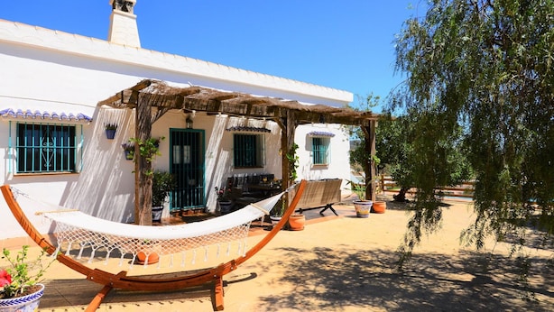 A white building with a thatched roof patio, a hammock, and potted plants. - Villa in Malaga, Private Pool and sea View (Cartama)