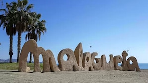 A beach with large, sculptural letters spelling "Malagueta" made of stone. - Villa in Malaga, Private Pool and sea View (Cartama)