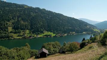 A lake surrounded by forested hills with a small building in the foreground.