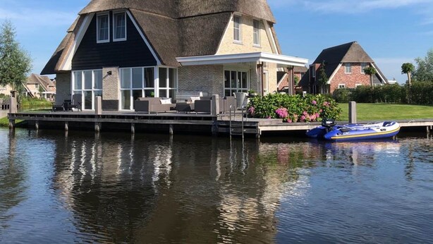 A house with a thatched roof, a dock, and a boat. - Villa in Friesland With Sauna and Jetty (Delfstrahuizen)