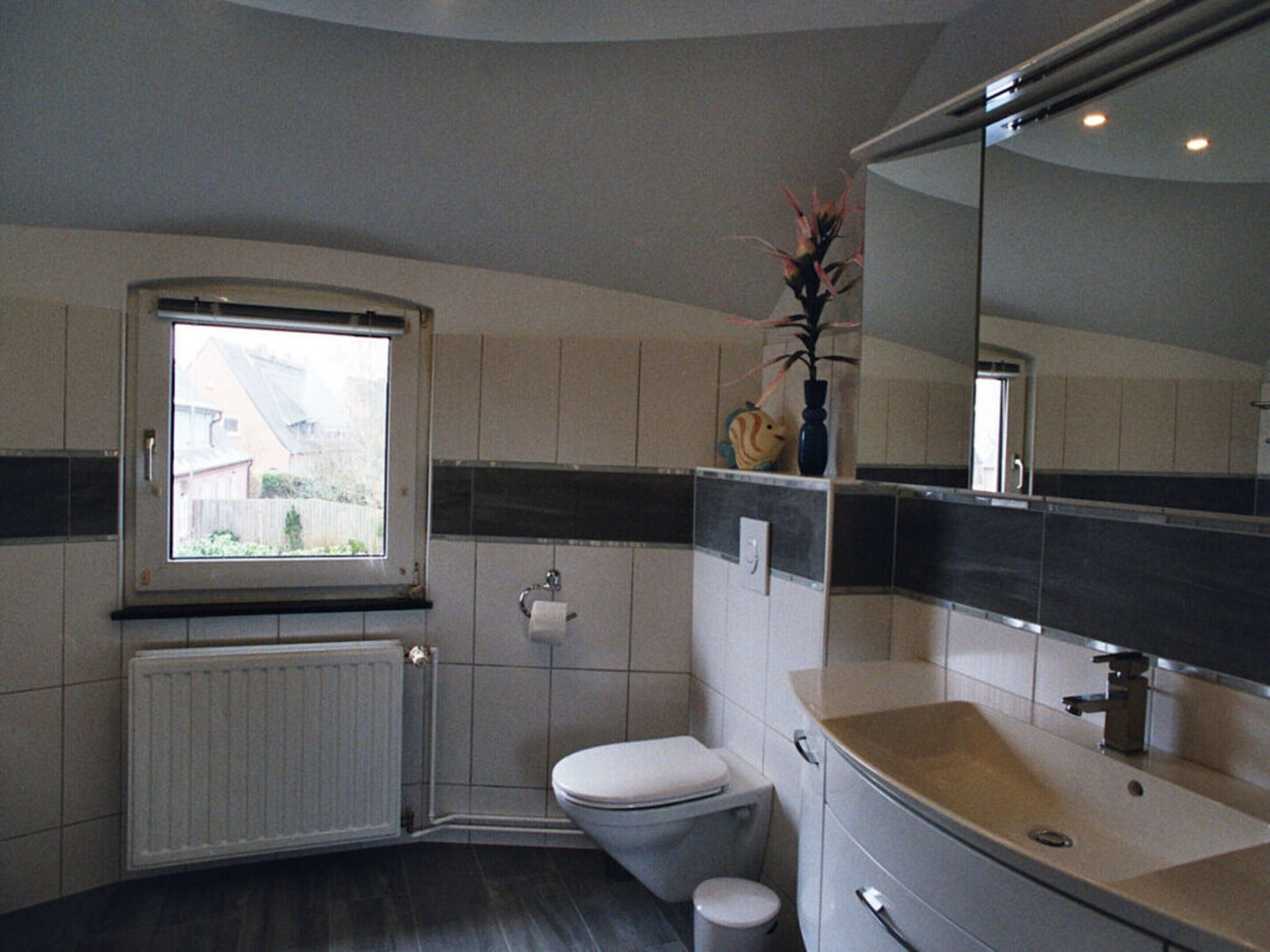 Une salle de bain avec des toilettes, un lavabo et une fenêtre.