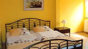 Quarto com cama, mesa de cabeceira, abajur e um quadro na parede.