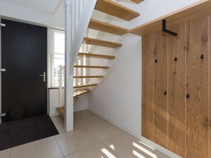 A modern interior with a wooden staircase, a dark door, and a large wooden panel wall. - Beautiful Villa With Wellness (Delfstrahuizen)