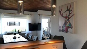 Een moderne eetruimte met een houten tafel, stoelen, een televisie en een schilderij van een hert.