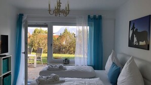 Een slaapkamer met twee bedden, een televisie en uitzicht op een tuin en bergen.