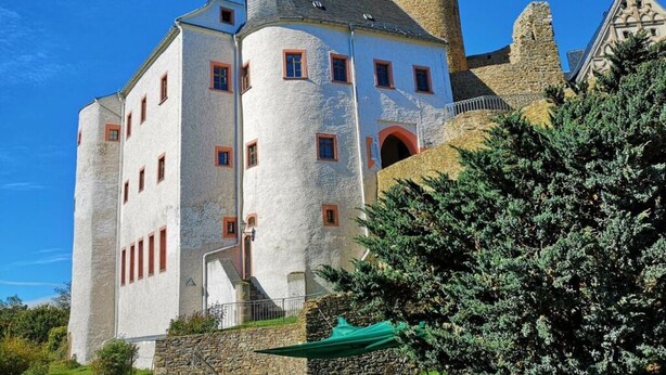Un bâtiment qui ressemble à un château, avec une tour en pierre et de nombreuses fenêtres.
