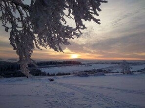 A snowy landscape with a sunset, a clear sky, and a distant tree line. - Old Forge Modern Retreat (Drebach)