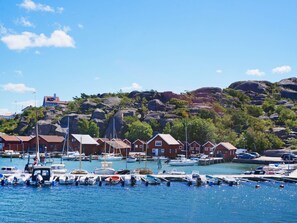 A harbor with boats docked, red-roofed buildings, and rocky hills in the background. - 4 Star Holiday Home in Bovallstrand (Bovallstrand)