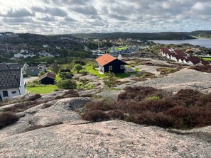 A coastal village with houses on rocky terrain, a body of water in the background, and a cloudy sky. - 4 Star Holiday Home in Bovallstrand (Bovallstrand)