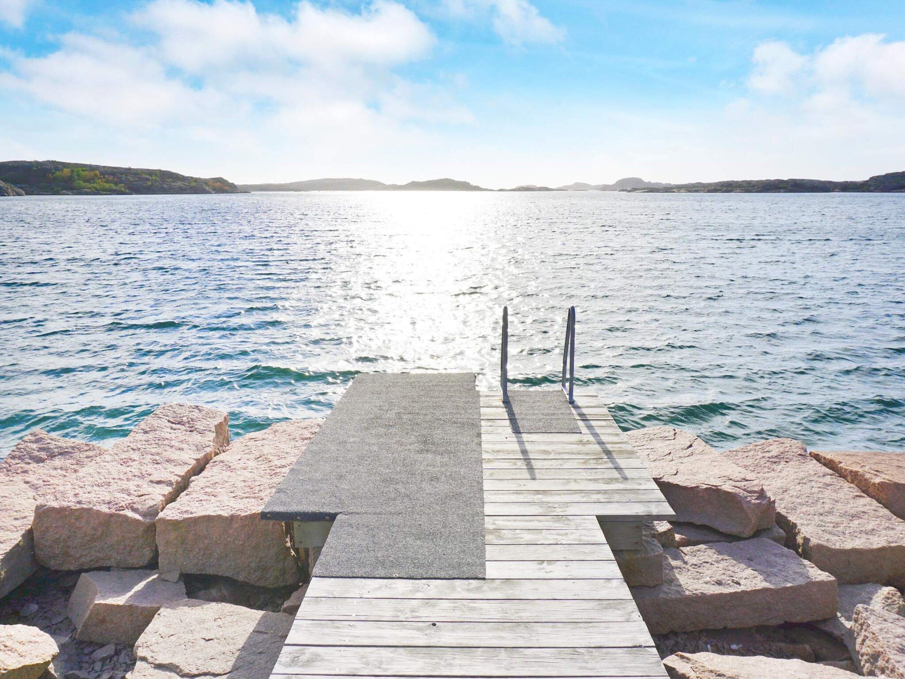 A wooden pier leading into a calm body of water with a clear sky above.