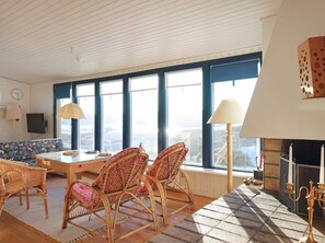 Un salon chaleureux avec un canapé, des fauteuils en osier, une table basse et une cheminée.