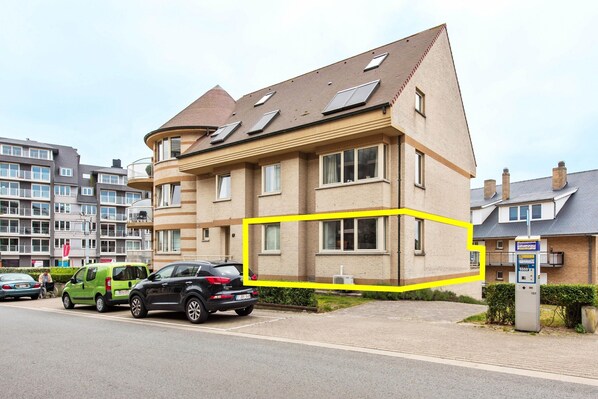 Un edificio residencial de diseño moderno, con múltiples ventanas y un techo inclinado con paneles solares.