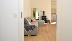 A modern living room with a sofa, a small round table, and a kitchen visible through an open door. - Your Coastal Hideaway (Kamperland)