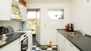 A compact kitchen with white cabinets, a black and white checkered floor, a coffee maker, and a window with a butterfly decoration. - 5 Person Holiday Home in Melby (Melby)