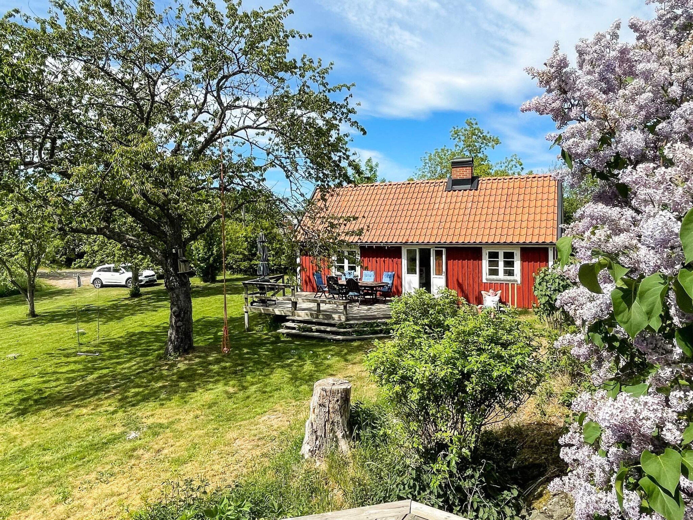 A red house with a tiled roof, a deck, and a lawn.