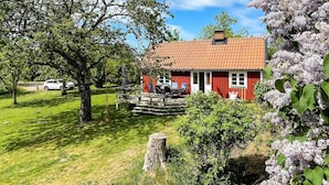 A red house with a tiled roof, a deck, and a lawn. - 4 Star Holiday Home in Torhamn (Torhamn)