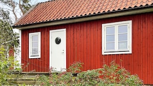 A red wooden building with a tiled roof, a white door, and two windows. - 4 Star Holiday Home in Torhamn (Torhamn)