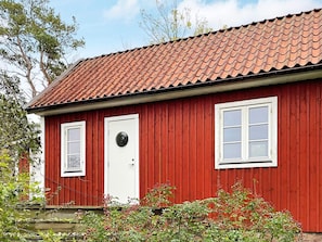 A red wooden building with a tiled roof, a white door, and two windows. - 4 Star Holiday Home in Torhamn (Torhamn)