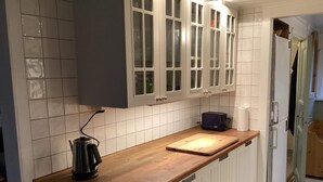 Ett kök med vita skåp, en träbänkskiva, en vattenkokare och en brödrost.