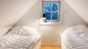 A small, single-room with two beds, a window with a view of trees, and a wooden floor. - 4 Star Holiday Home in Torhamn (Torhamn)