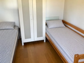 A bedroom with two single beds, a wardrobe, and a wooden floor. - 4 Star Holiday Home in Torhamn (Torhamn)