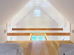 An attic bedroom with a sloped ceiling, wooden beams, a skylight, and a view of greenery outside. - 4 Star Holiday Home in Torhamn (Torhamn)
