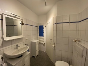 A compact bathroom with a white sink, mirror, and toilet. - Holiday Apartment Fischbude (Eckernfoerde)
