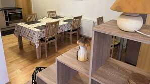 Un coin repas avec une table et des chaises, un téléviseur fixé au mur et une lampe sur une étagère.