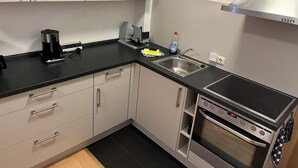Une cuisine moderne avec un plan de travail noir, des appareils en acier inoxydable et des meubles blancs.